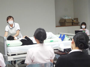 介護職員による入居者への身体介護・機能訓練の様子。ベッドでの処置風景。